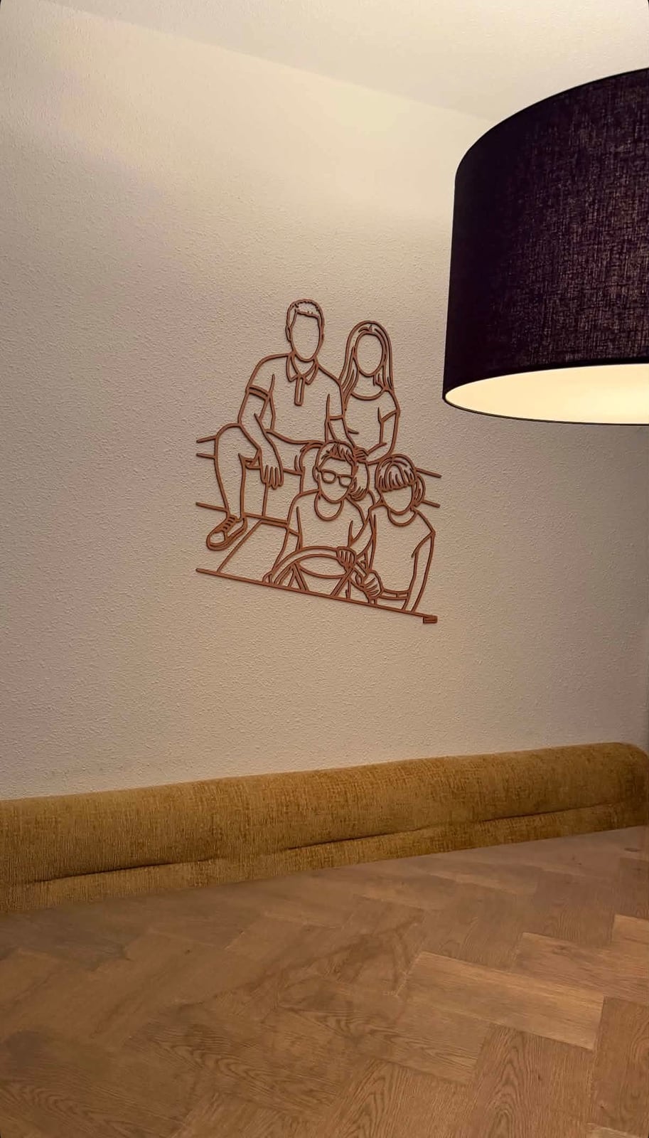 Linienporträt aus Holz einer Familie an der Wand, unter einer großen Hängelampe