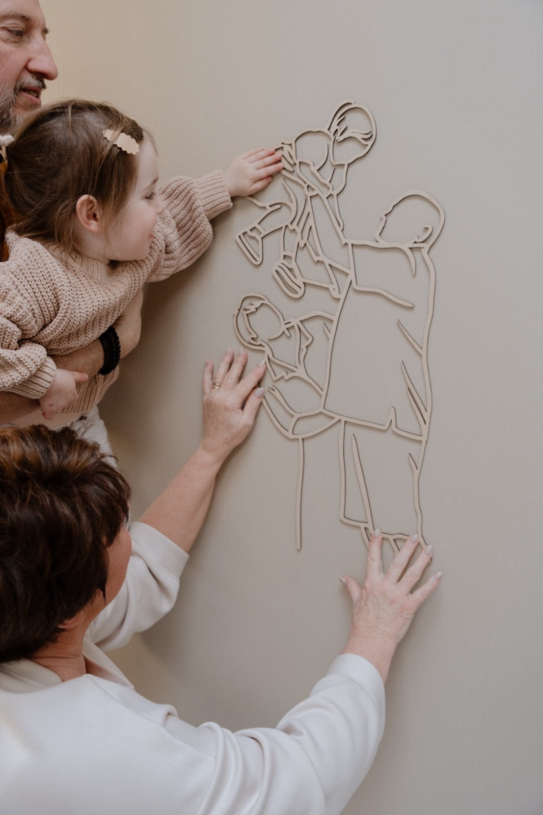 Des grands-parents accrochent le portrait linéaire en bois avec leur petite-fille