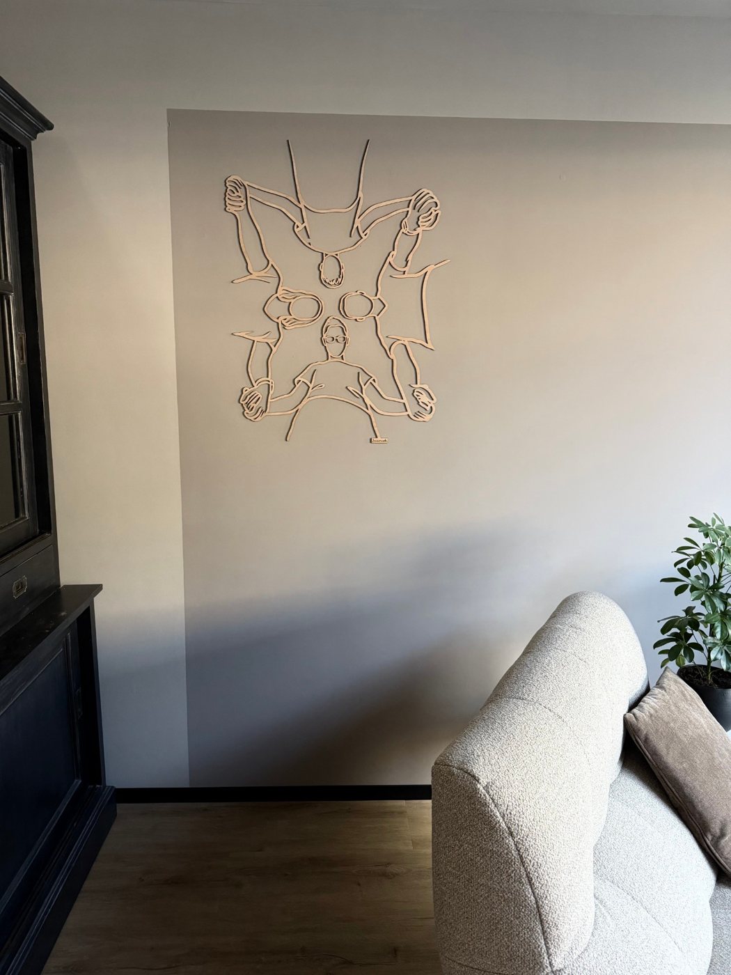 Houten lijnportret van vier personen van bovenaf, boven de zetel