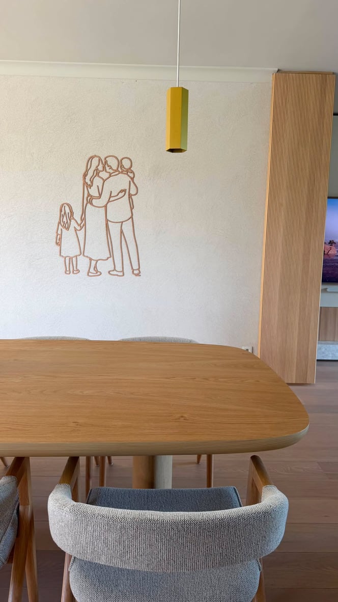 Linienporträt aus Holz einer Familie an der Wand über dem Esstisch